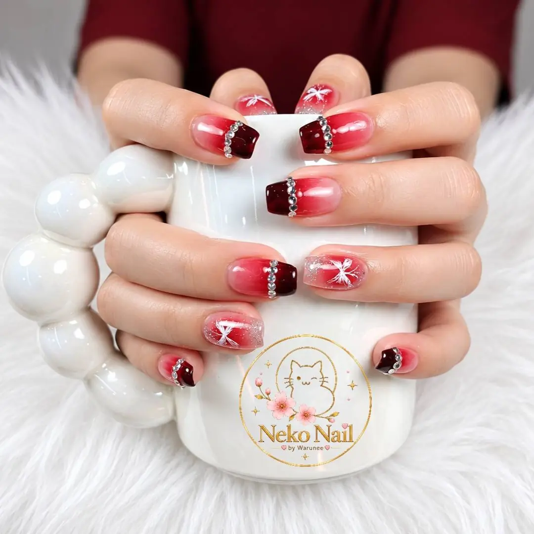เล็บเจลสีแดงเบอร์กันดีไล่สี ประดับคริสตัลและลายโบว์ขาว ผลงาน Neko Nail by Warunee บางใหญ่